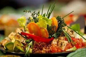 Un plato de comida con diversos vegetales y carne, adornado con hierbas aromáticas.