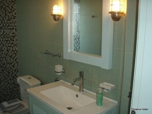 A bathroom with a white sink, a mirror, and two wall-mounted light fixtures. - Hotel Phoenix (Lefkada)