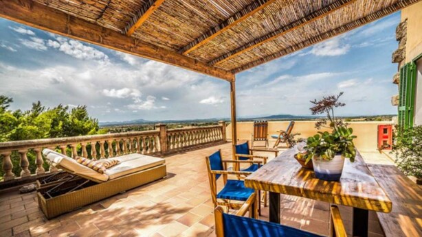 A terrace with a wooden table and chairs, a cushioned sofa, and a view of the landscape. - Rural Apartment Lledoner de Son Amer (Felanitx)