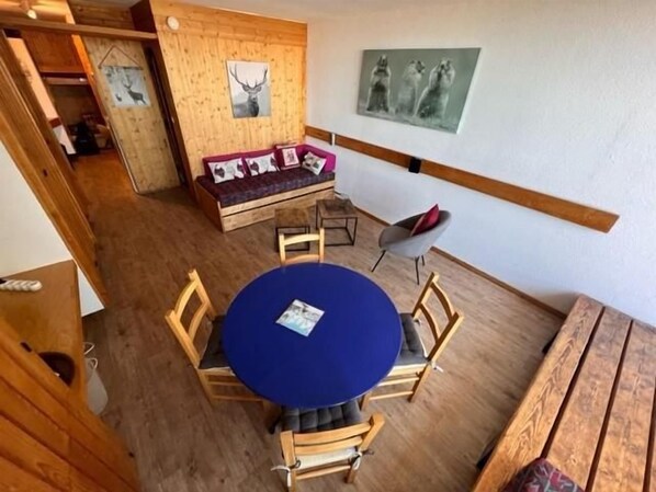 A room with a round table, wooden chairs, a sofa, and a wooden bench.