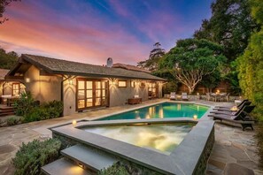 A modern house with a swimming pool, outdoor seating, and a well-lit patio area.