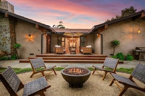 A patio with a fire pit, outdoor seating, and a view of the house entrance.