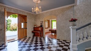 Una habitación amplia con suelo a cuadros, un piano de cola y una araña.