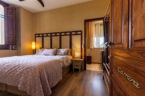 Une chambre à coucher avec un grand lit, des lampes de chevet, une tête de lit en bois, une armoire et une fenêtre avec des rideaux.