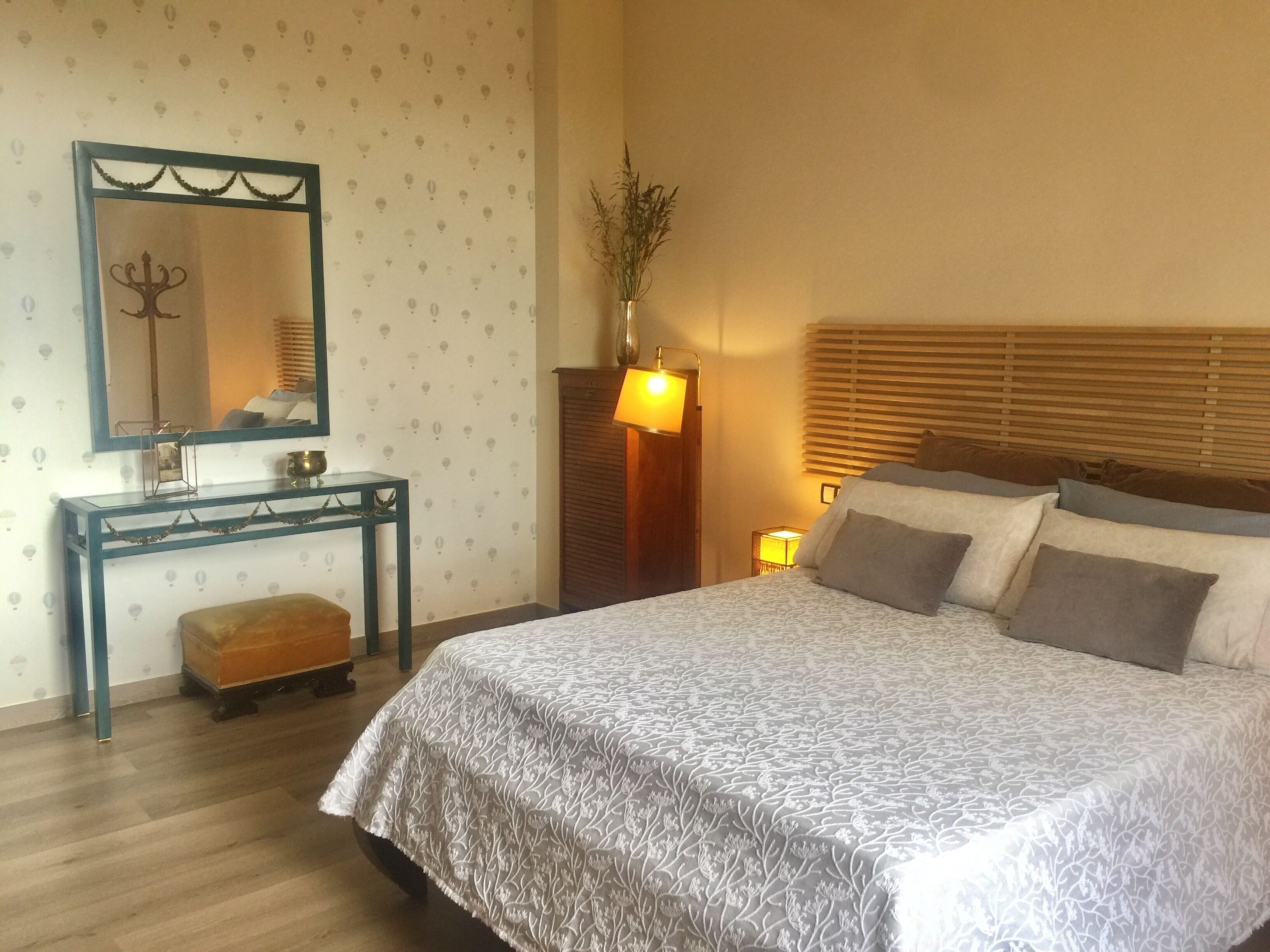 Ein Schlafzimmer mit Bett, Nachttisch, Lampe und Spiegel.