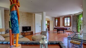 Amplia sala de estar con mesa de billar, televisor y sofá.