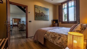 Un dormitorio con una cama, un cuadro de un puente, una ventana y un ventilador de techo.