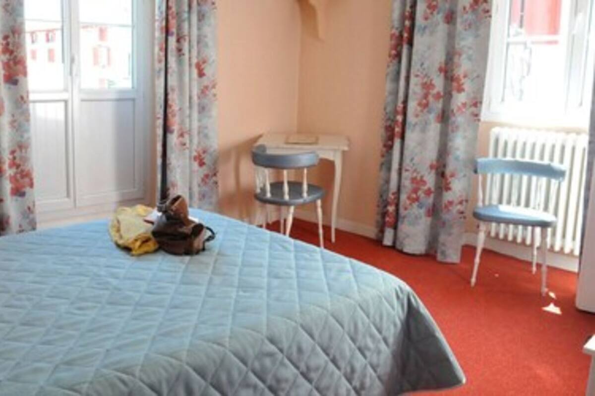 A bedroom with a bed, a desk, two chairs, and a radiator.