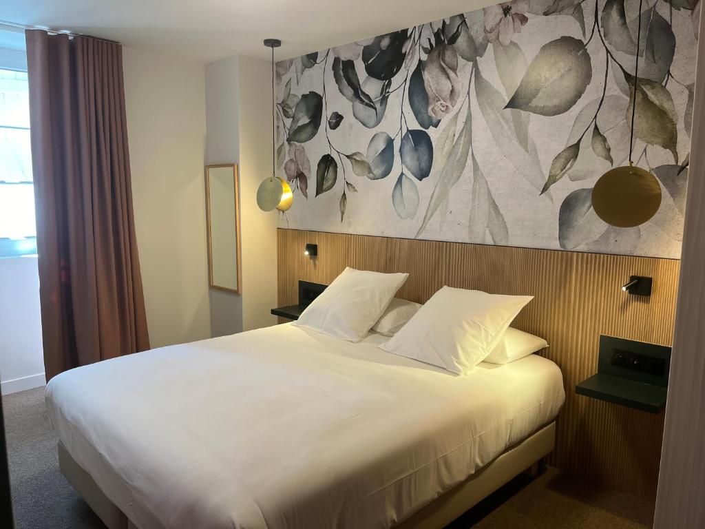 A hotel room with a large bed, a wooden headboard, a wall-mounted lamp, and a nightstand.