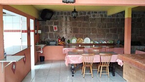 Una cocina con pared de piedra, un lavamanos y una mesa con sillas.
