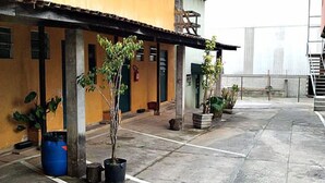 Un patio con plantas en macetas, un barril azul y un edificio con tejado de tejas.