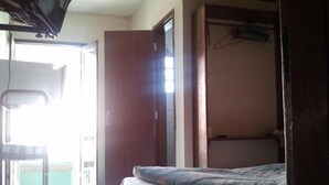 Un dormitorio con cama, una silla y un armario.