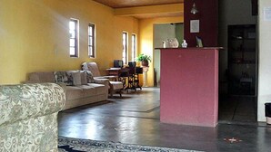 Una sala de estar con un sofá, una mesa de comedor y sillas. Hay una zona de cocina con un refrigerador y un lavaplatos.
