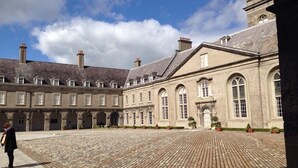 Une cour intérieure avec un bâtiment historique doté d’arches au niveau des fenêtres et d’un sol carrelé.