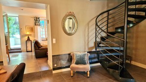 A spacious living area with a modern staircase, a comfortable seating area, and a decorative mirror on the wall.