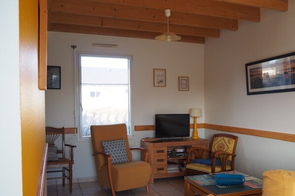 Ein Wohnzimmer mit Fernseher, Holzmöbeln und einem Fenster.