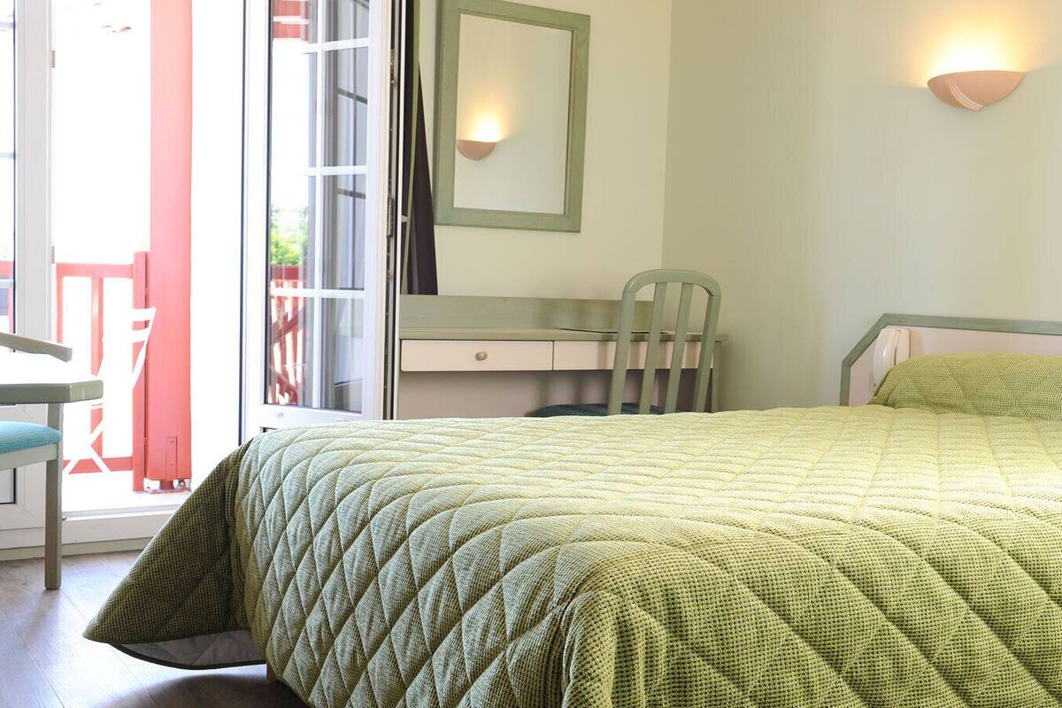 A bedroom with a bed, a desk, and a chair.