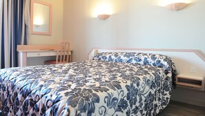 Ein Hotelzimmer mit Bett, Schreibtisch, Stuhl und Nachttisch.