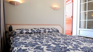 Een slaapkamer met een bed, een telefoon en een raam met gordijnen.