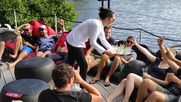 Un gruppo di persone sul ponte di una barca, con un microfono e un vassoio di bevande.