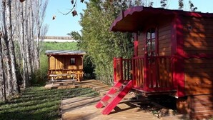 A wooden cabin with a red exterior, a wooden deck, and a ladder leading to the entrance. - Provence Roulottes Hébergement insolite (Barbentane)