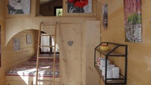 A wooden interior with a loft bed, a ladder, and a shelf with white mugs. - Provence Roulottes Hébergement insolite (Barbentane)