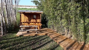 Uma cabana de madeira com mesa de piquenique e um deck de madeira que a leva até ela.