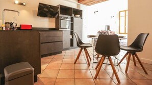 Una cocina moderna con comedor, que incluye horno empotrado, pileta y una mesa con sillas.