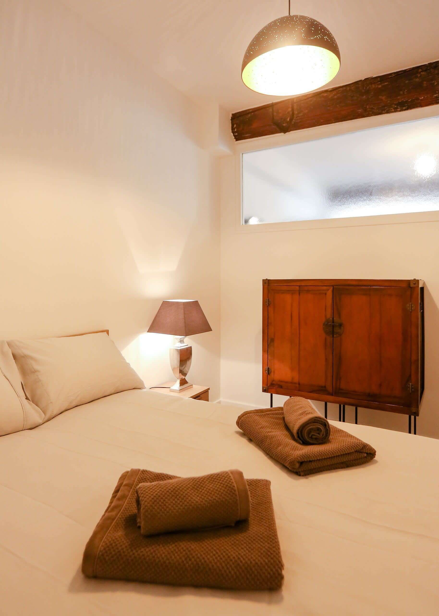 Un dormitorio con una cama, un armario de madera, una lámpara y una ventana.