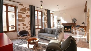 Una sala de estar con sofá, sillón, mesa de centro y chimenea.