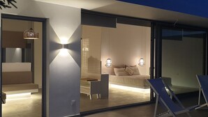 A modern bedroom with a large bed, bedside lamps, and a view through a glass door. - Fiore Suites (Zakynthos)