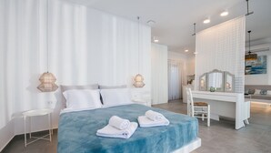 A modern bedroom with a large bed, a desk, and a chair. - Fiore Suites (Zakynthos)