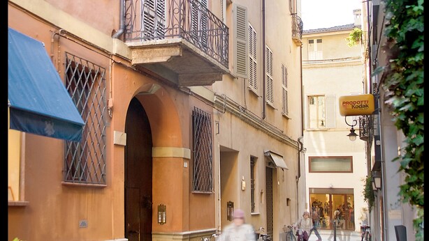 Eine enge Straße mit Häusern, die Balkone und Fensterläden haben.