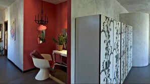 Ein modernes Interieur mit roter Akzentwand, einer weißen Toilette und einem dekorativen Spiegel.
