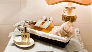 Ein Badezimmer-Waschtisch mit Parfumflakon, Handtuch und einer dekorativen Lampe.