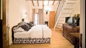 Ein Schlafzimmer mit einem Bett, einem Fernseher und einer Treppe.