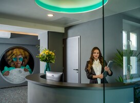 Uma área de recepção com balcão, um vaso de flores, uma porta e uma parede com desenho circular.