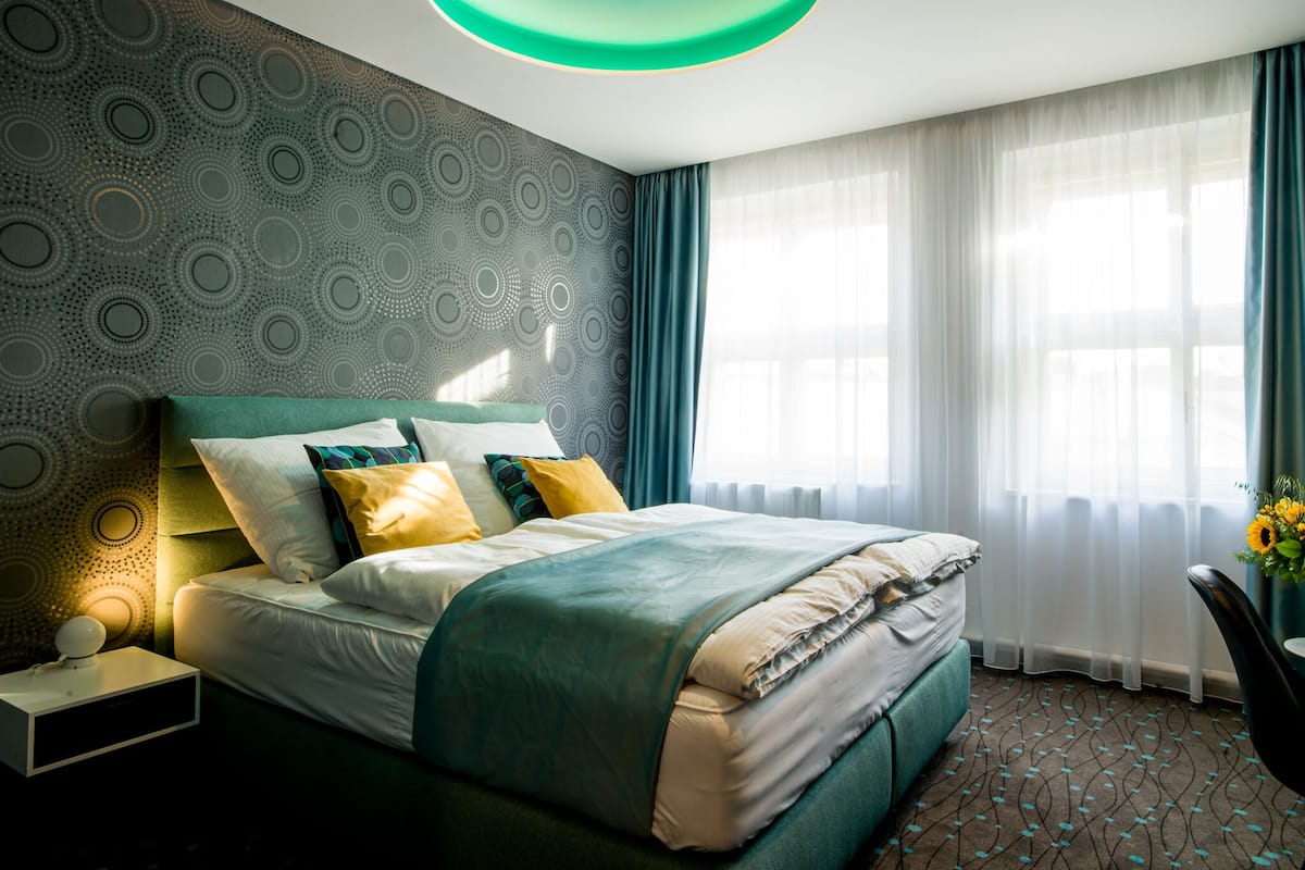 A modern bedroom with a bed, a nightstand, a desk, and a chair.
