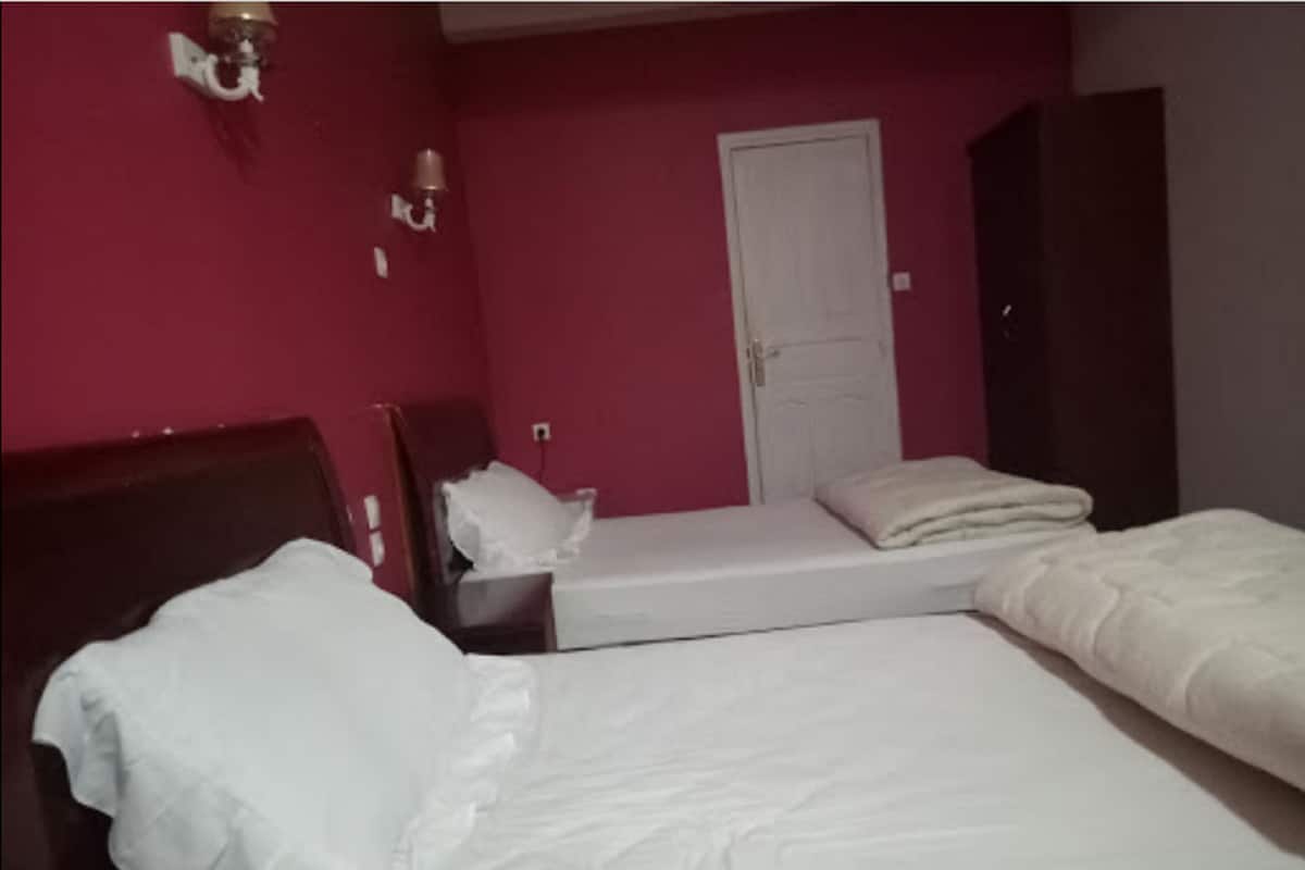 A room with two beds, a wardrobe, and a door.