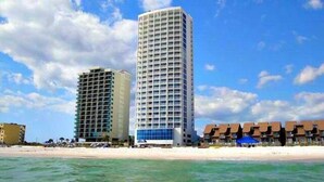 A beachfront hotel with a modern design, featuring a prominent glass facade and a series of balconies. - 🌴Things are different at the beach! It's relaxing season all year long.🚤🐬 (Gulf Shores)