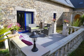 Un bâtiment en pierre doté d’un patio am énagé avec du mobilier d’extérieur et une lanterne.