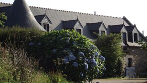 A building with a steeply pitched roof and multiple dormer windows. - Ti Anna Breizh cottage label 4 * (Lannilis)