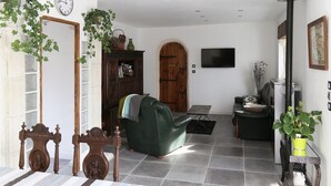 A living room with a green sofa, a wooden cabinet, a TV, and a fireplace. - Ti Anna Breizh cottage label 4 * (Lannilis)