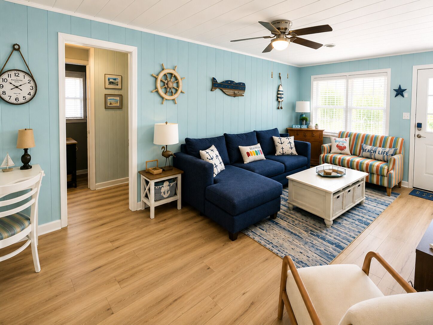 A living room with a blue sofa, a striped armchair, a coffee table, and a ceiling fan.