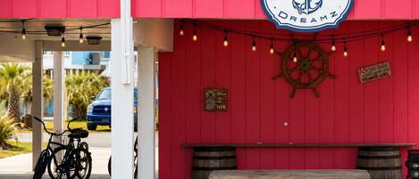 A red building with a nautical sign, a bicycle, and a wooden bench.