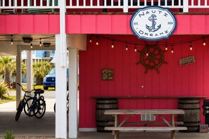 A red building with a nautical sign, a bicycle, and a wooden bench.