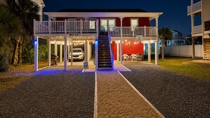 Un bâtiment à deux étages doté d’une entrée couverte, une voiture garée à l’intérieur et un escalier menant à l’étage supérieur.