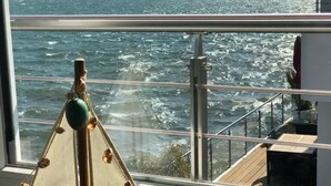 Vista desde la cubierta de un barco, con barandilla y un objeto decorativo en primer plano.