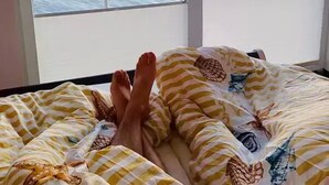 Una habitación con una cama orientada a un gran ventanal con vistas a un cuerpo de agua al atardecer.