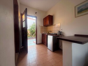 A compact kitchen with a refrigerator, a sink, and wooden cabinets. - Margarita Apartments (Corfu)